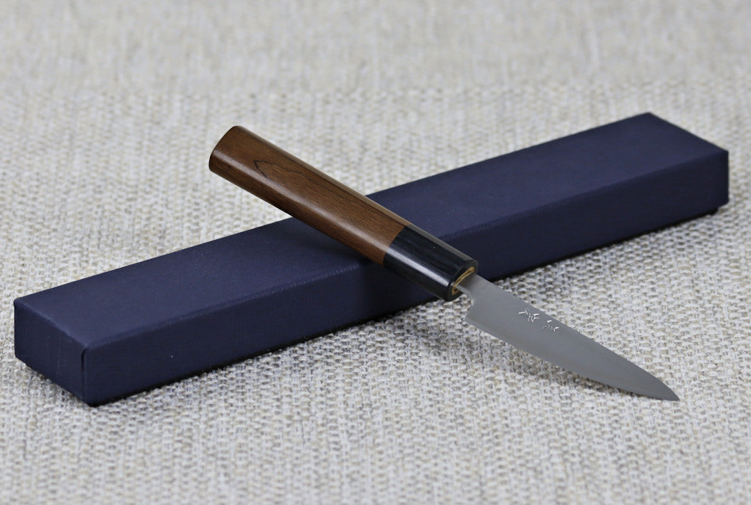 Akifusa's 80mm Paring knife, Aogami Super steel with the Migaki (polished finish resting against the packaging