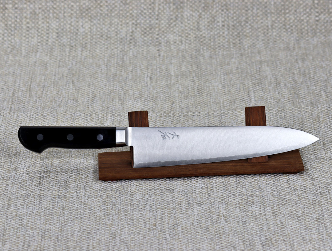 Ohishi VG5 Migaki 210mm Gyuto (Chef) Japanese kitchen knife, resting on a red wood stand