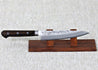 Ohishi Ginsan 135mm Petty (Utility) Japanese Kitchen knife resting on a red wood knife stand showing the Nashiji (Pear skin) finish.