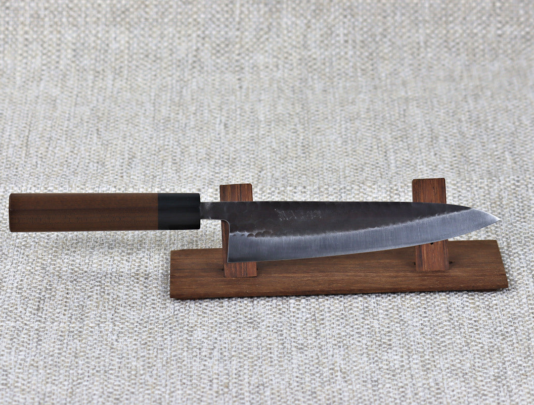 Ohishi Aogami 2 Kurouchi/Tsuchime 180mm Gyuto(Chef) kitchen knife on a red wood stand 
