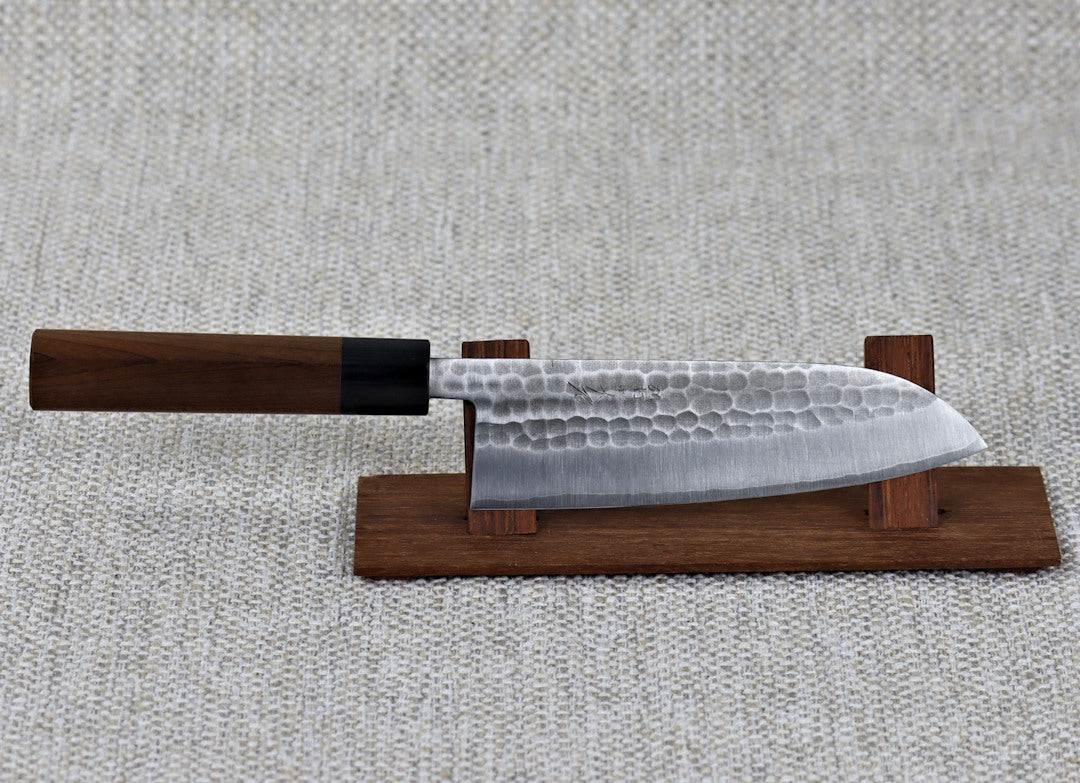 Ohishi SLD 165mm Santoku(General Purpose) Japanese Kitchen Knife mounted on a red wood knife stand really emphasising the tsuchime (hammered) finish on the blade