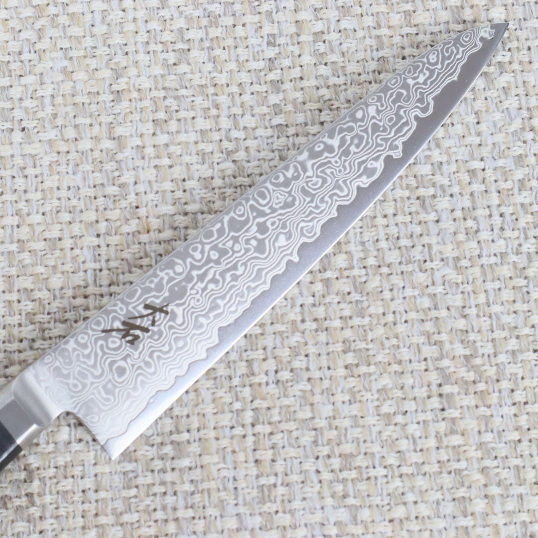 Ohishi Classic Powder Metal Damascus 150mm Petty (Utility) Japanese kitchen knife close up of the "Floating Ink" Damascus blade and the makers mark on the blade
